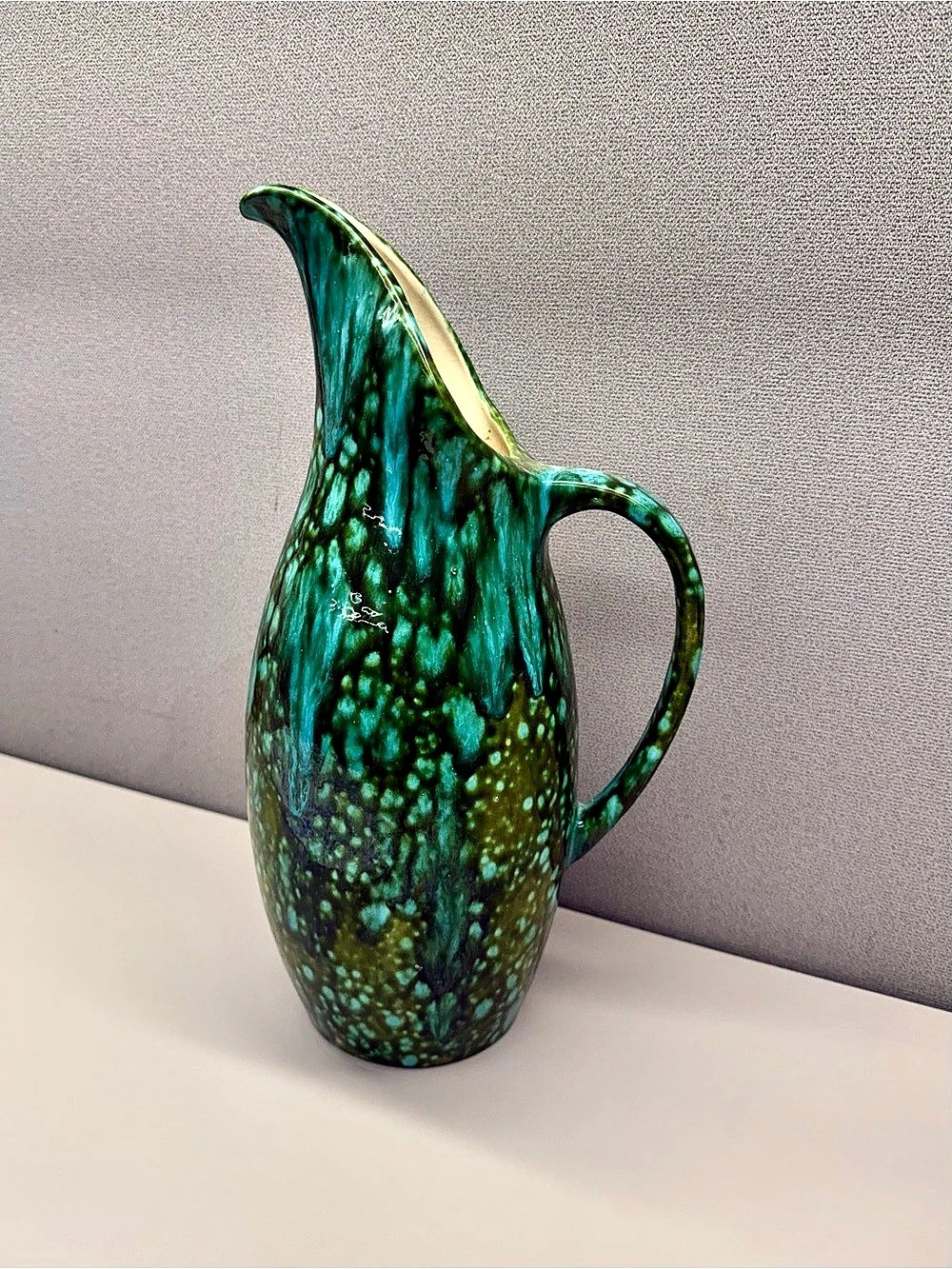 A vintage mid-century modern ceramic pitcher featuring a striking speckled gree